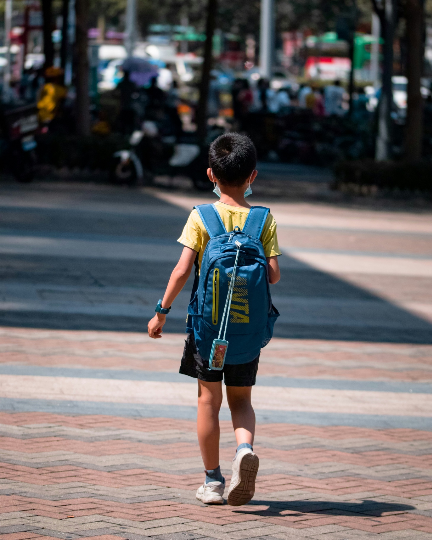 A child in a bright doorway, backpack on, morning light on their face