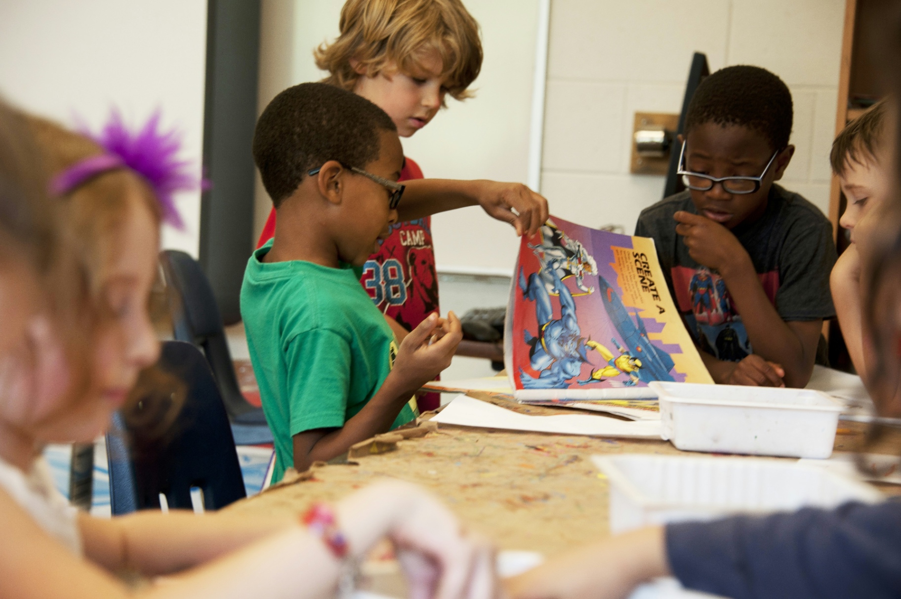 Children collaborating around a shared table, hands and workbooks in focus